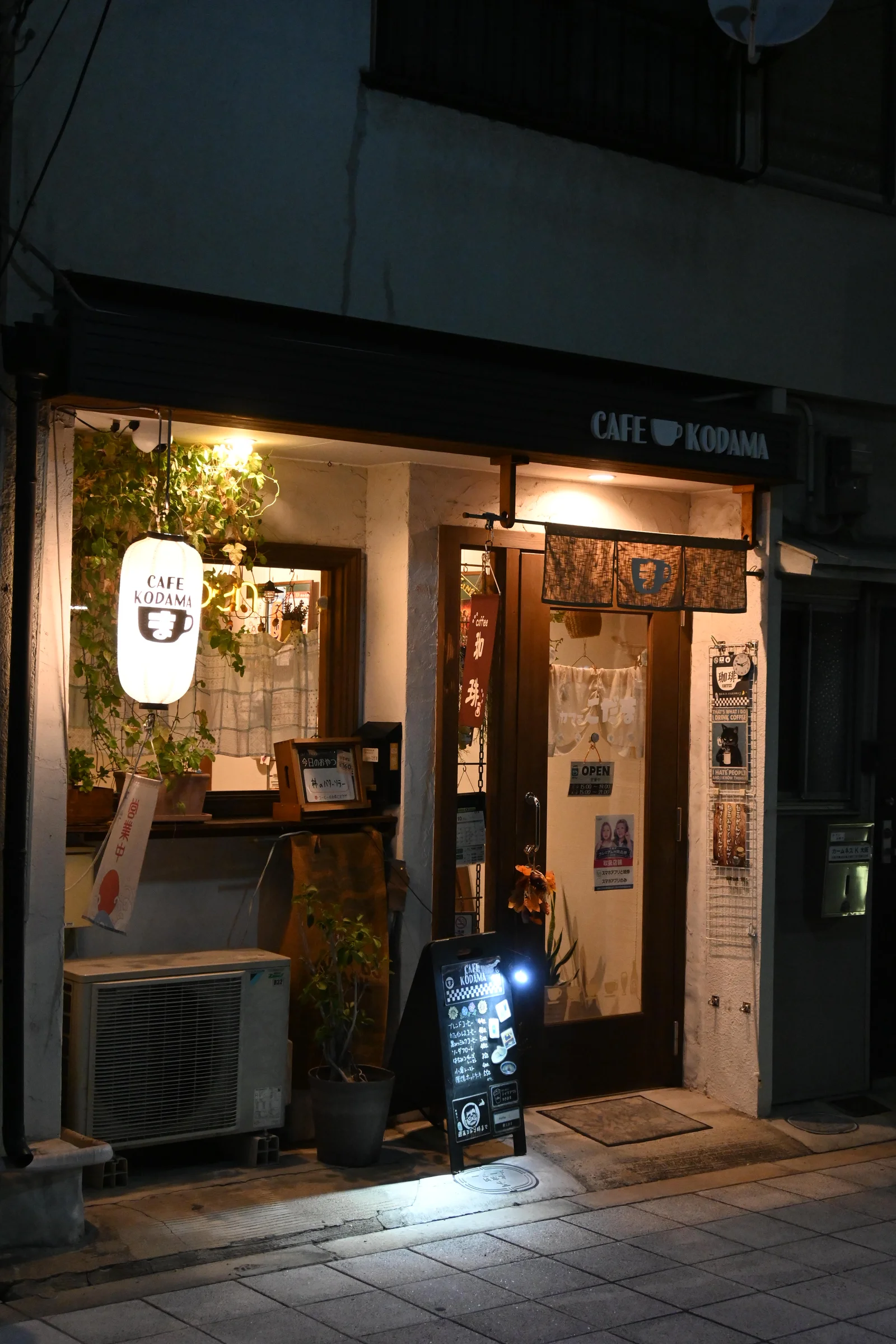 カフェこだまの外観。灯りのついた入口と店名の看板